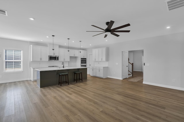 kitchen featuring pendant lighting, appliances with stainless steel finishes, white cabinetry, a large island, and ceiling fan