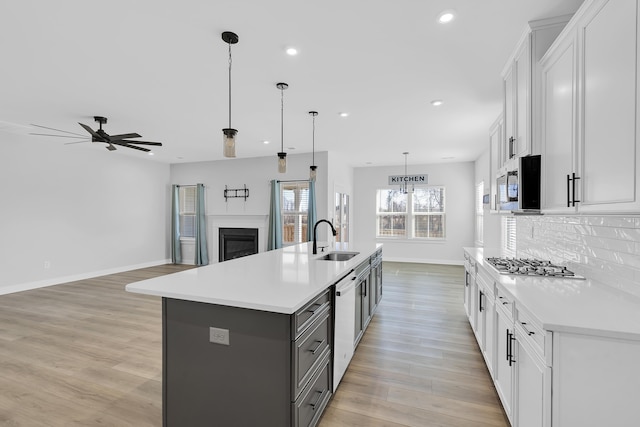 kitchen with white cabinets, an island with sink, stainless steel appliances, and pendant lighting