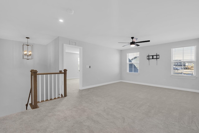 unfurnished room with light carpet, a healthy amount of sunlight, and ceiling fan with notable chandelier