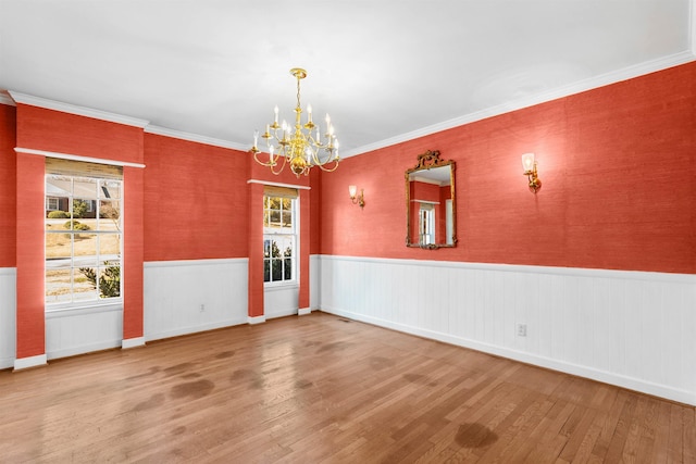 spare room featuring a notable chandelier, ornamental molding, and hardwood / wood-style flooring