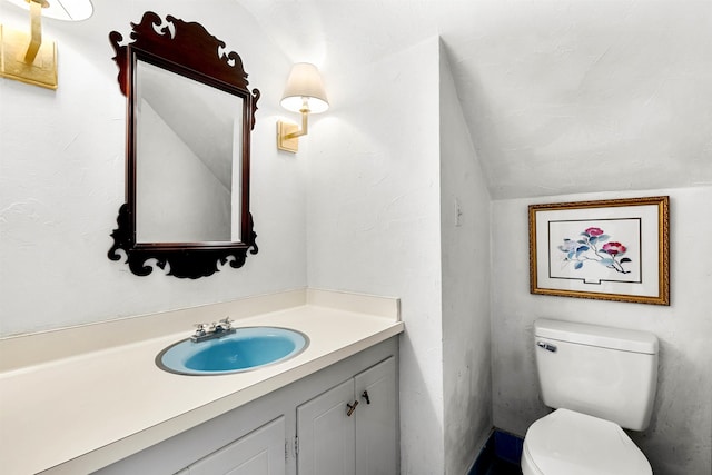 bathroom with toilet, lofted ceiling, and vanity