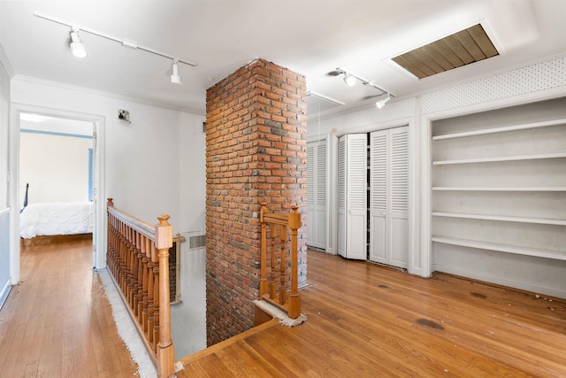 hall with built in shelves, crown molding, and light hardwood / wood-style flooring