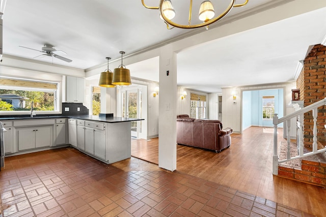 kitchen with ceiling fan with notable chandelier, white cabinetry, decorative backsplash, kitchen peninsula, and crown molding