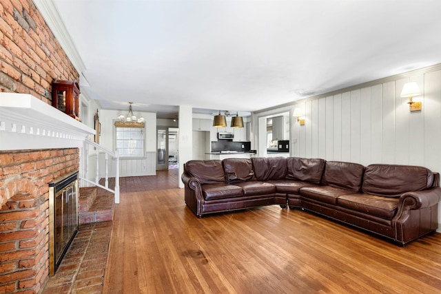 living room featuring a fireplace, wood-type flooring, and a notable chandelier