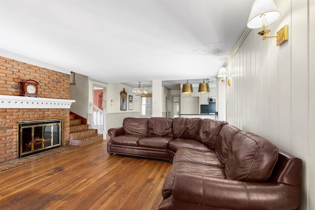 living room with a fireplace, wood walls, ornamental molding, and hardwood / wood-style floors