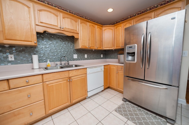 kitchen featuring decorative backsplash, sink, stainless steel fridge, white dishwasher, and light tile patterned floors