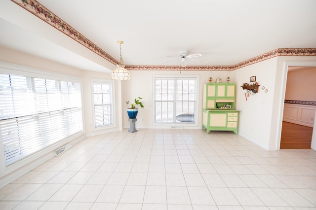 tiled empty room featuring ceiling fan and a healthy amount of sunlight