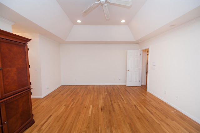 empty room featuring light wood-type flooring, ceiling fan, lofted ceiling, and a raised ceiling