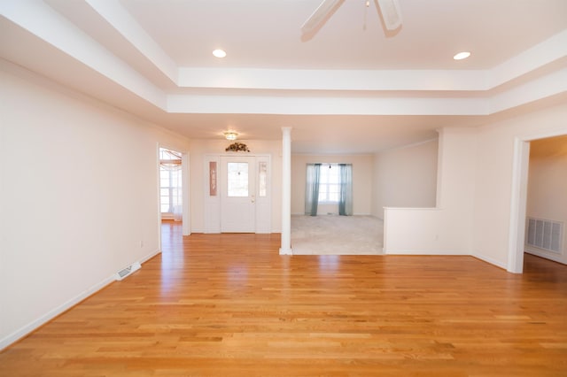 interior space with ceiling fan, a raised ceiling, and light hardwood / wood-style flooring