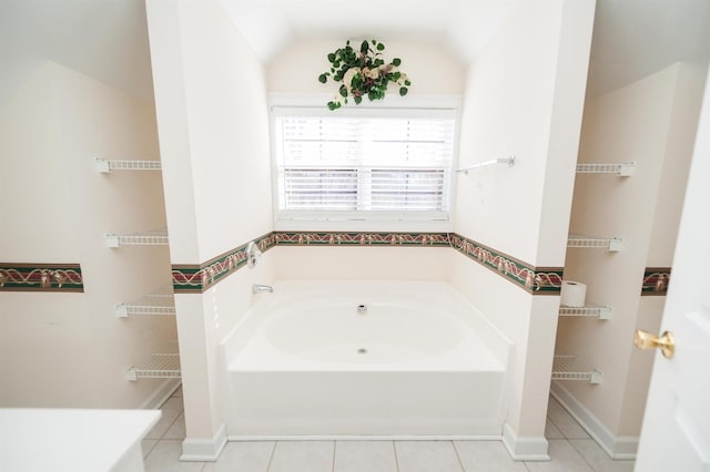 bathroom featuring a tub, lofted ceiling, and tile patterned flooring