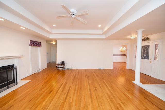 unfurnished living room with ceiling fan, ornate columns, light hardwood / wood-style floors, and a raised ceiling