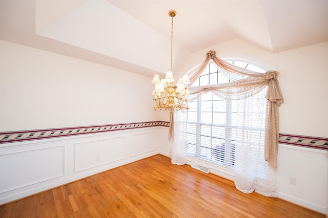 unfurnished room featuring vaulted ceiling, a chandelier, and hardwood / wood-style floors