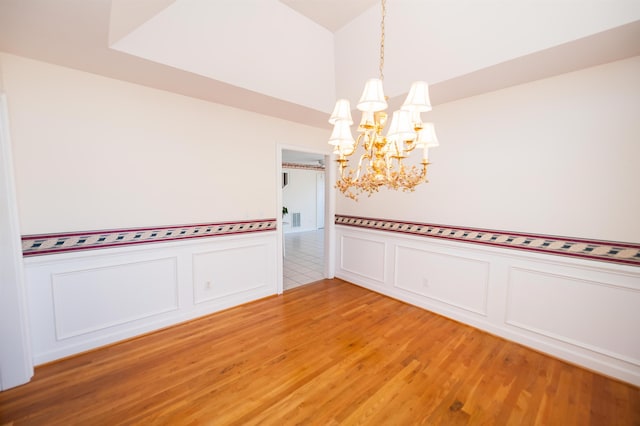 spare room with a chandelier and hardwood / wood-style flooring