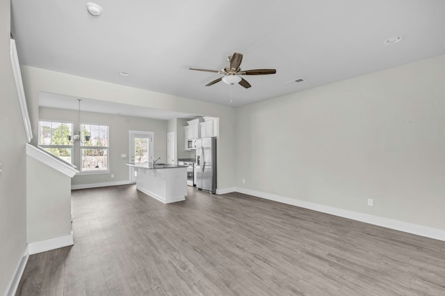 unfurnished living room featuring ceiling fan with notable chandelier, dark hardwood / wood-style floors, and sink