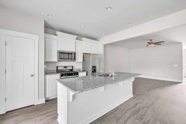 kitchen with a kitchen breakfast bar, appliances with stainless steel finishes, white cabinetry, and a kitchen island with sink