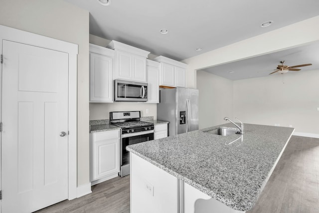 kitchen with light stone countertops, appliances with stainless steel finishes, white cabinetry, and sink