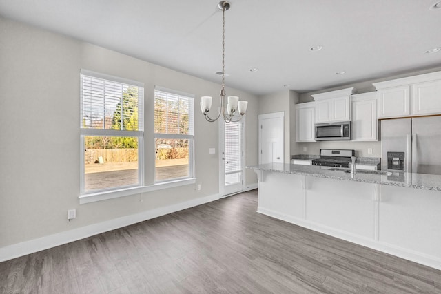 kitchen featuring white cabinetry, stainless steel appliances, decorative light fixtures, dark wood-type flooring, and light stone countertops