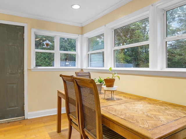 dining room with light wood-type flooring, a wealth of natural light, and ornamental molding