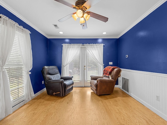 living area with ceiling fan, light hardwood / wood-style flooring, ornamental molding, and french doors