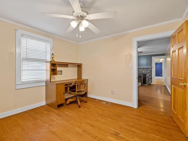 home office with light wood-type flooring, ceiling fan, crown molding, and a fireplace