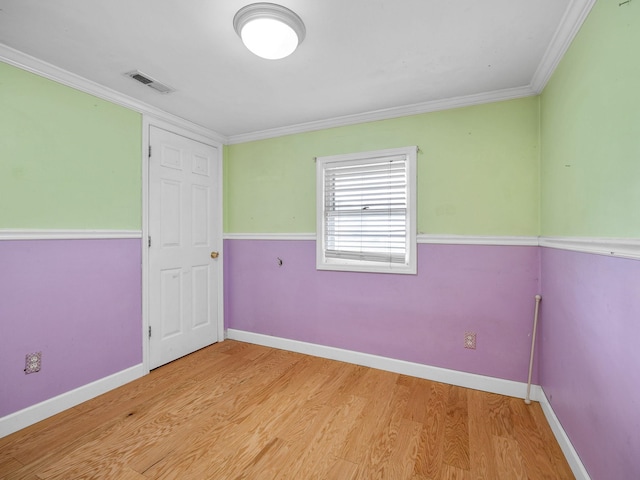 spare room featuring crown molding and light hardwood / wood-style flooring