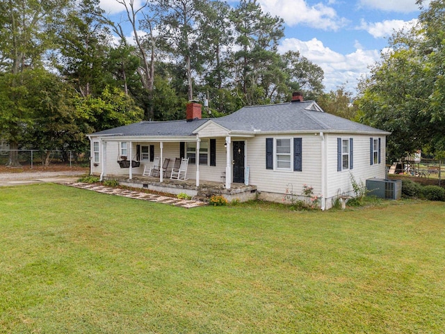 ranch-style home with central air condition unit, a front lawn, and covered porch