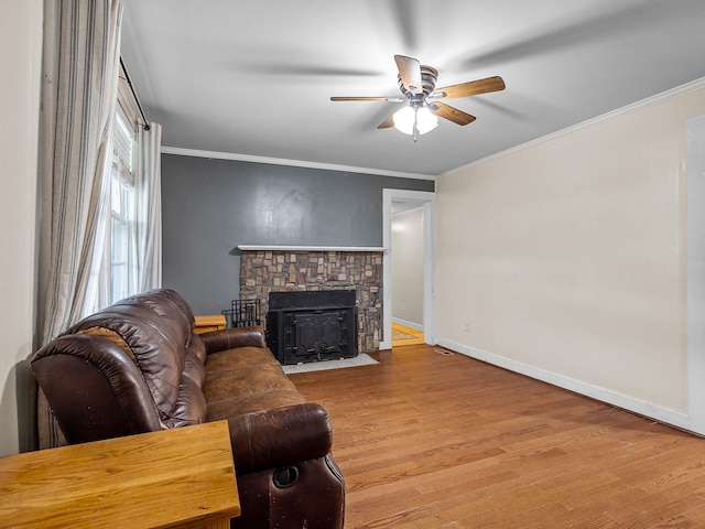 living room featuring ceiling fan, crown molding, a fireplace, and light hardwood / wood-style floors