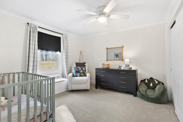 bedroom featuring ceiling fan, a closet, ornamental molding, and a crib