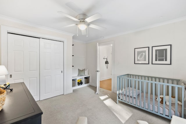 carpeted bedroom featuring ceiling fan, ornamental molding, a closet, and a nursery area