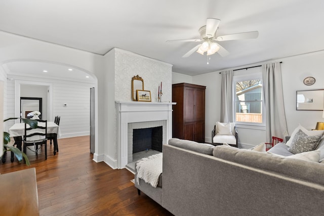 living room featuring dark wood-type flooring, ceiling fan, and a fireplace