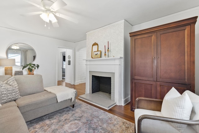 living room featuring ceiling fan, a brick fireplace, and dark hardwood / wood-style floors