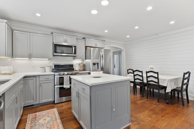 kitchen with dark hardwood / wood-style floors, appliances with stainless steel finishes, gray cabinetry, and a kitchen island