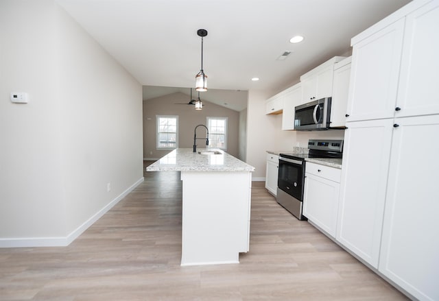 kitchen with vaulted ceiling, white cabinetry, appliances with stainless steel finishes, and a center island with sink