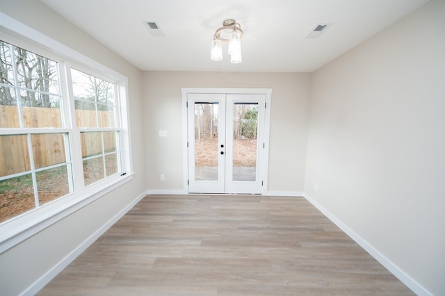 interior space with french doors, an inviting chandelier, and light hardwood / wood-style floors