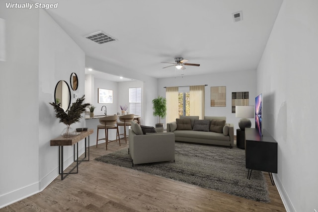 living room featuring ceiling fan, wood-type flooring, and sink