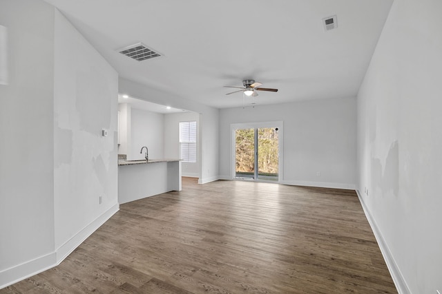 unfurnished living room with ceiling fan, wood-type flooring, and sink