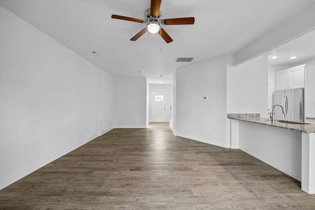 unfurnished living room featuring ceiling fan, dark hardwood / wood-style flooring, and sink