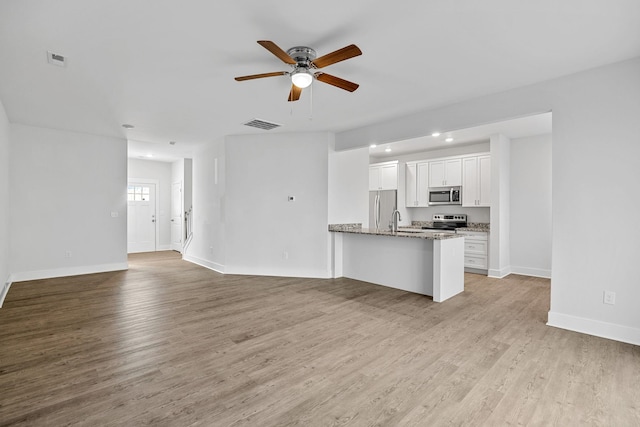 kitchen featuring kitchen peninsula, light hardwood / wood-style flooring, light stone countertops, stainless steel appliances, and white cabinets