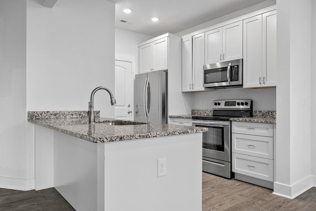 kitchen with sink, light stone counters, stainless steel appliances, and white cabinetry