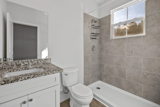 bathroom featuring toilet, vanity, and tiled shower