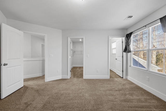 unfurnished bedroom featuring a spacious closet, a closet, carpet flooring, and multiple windows