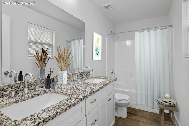 full bathroom featuring toilet, vanity, hardwood / wood-style flooring, and shower / bathtub combination with curtain