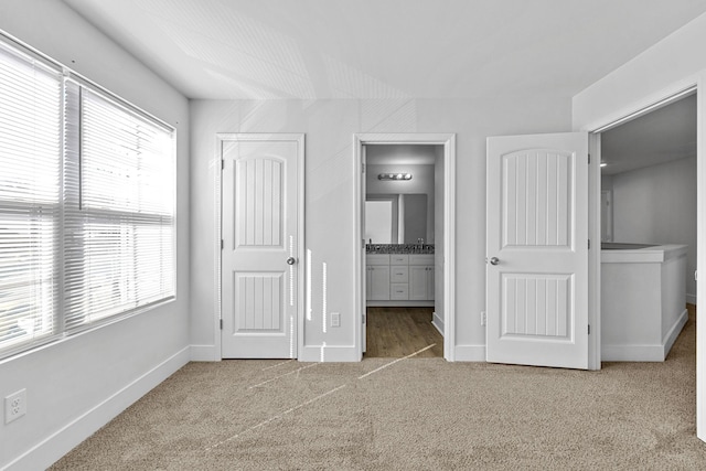 unfurnished bedroom featuring light carpet and ensuite bath