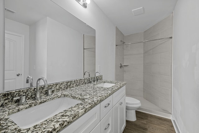 bathroom featuring toilet, tiled shower, hardwood / wood-style flooring, and vanity