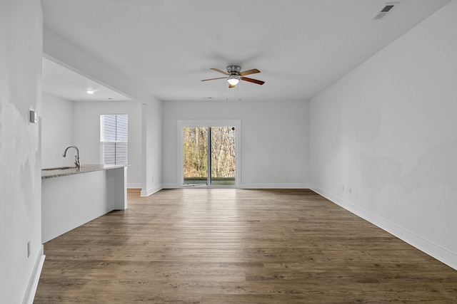 unfurnished living room featuring ceiling fan, sink, and dark hardwood / wood-style floors