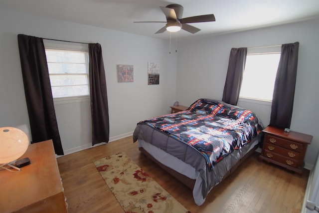 bedroom with ceiling fan, multiple windows, and hardwood / wood-style floors