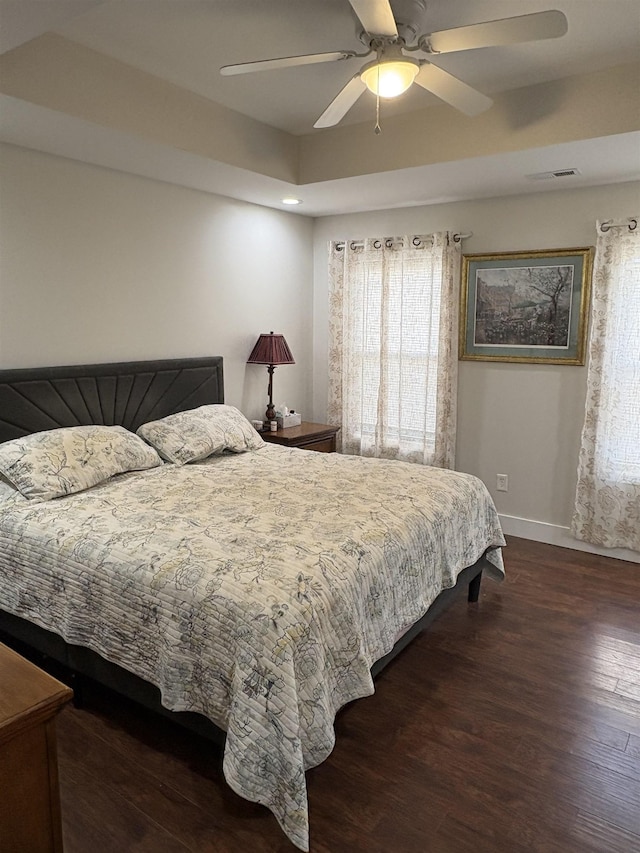 bedroom featuring ceiling fan, a tray ceiling, and multiple windows