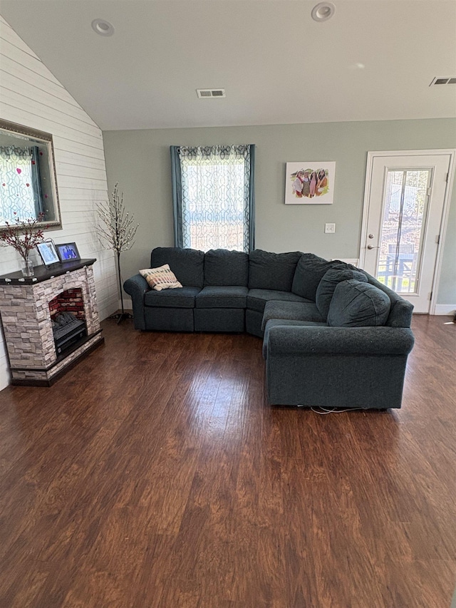 living room featuring dark hardwood / wood-style flooring, lofted ceiling, a fireplace, and plenty of natural light