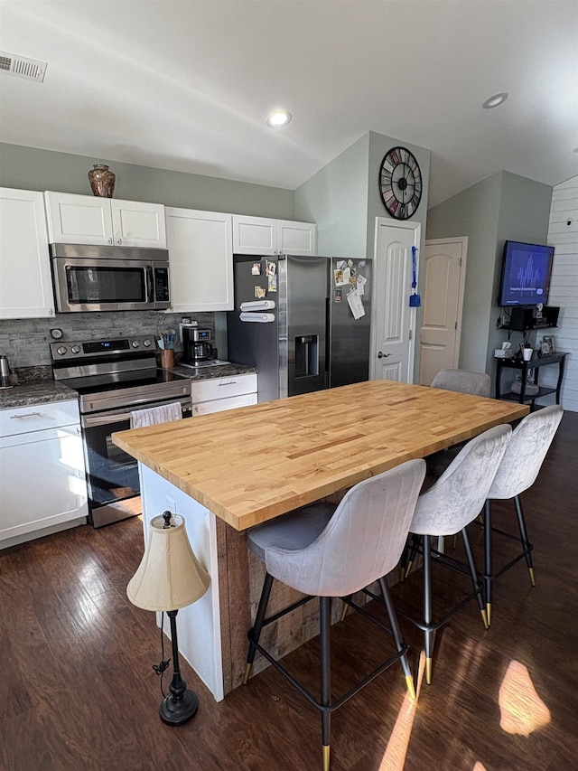 kitchen featuring wooden counters, a breakfast bar, white cabinetry, dark wood-type flooring, and stainless steel appliances