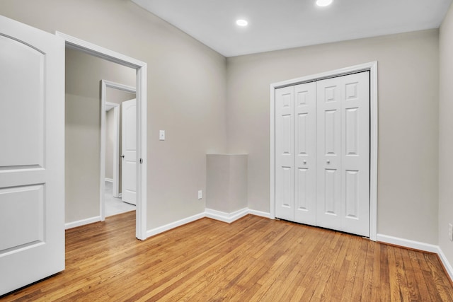 unfurnished bedroom with a closet, vaulted ceiling, and light hardwood / wood-style flooring